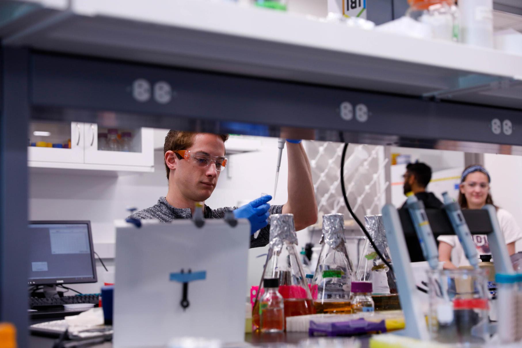 male student with goggles and chemical testing equipment